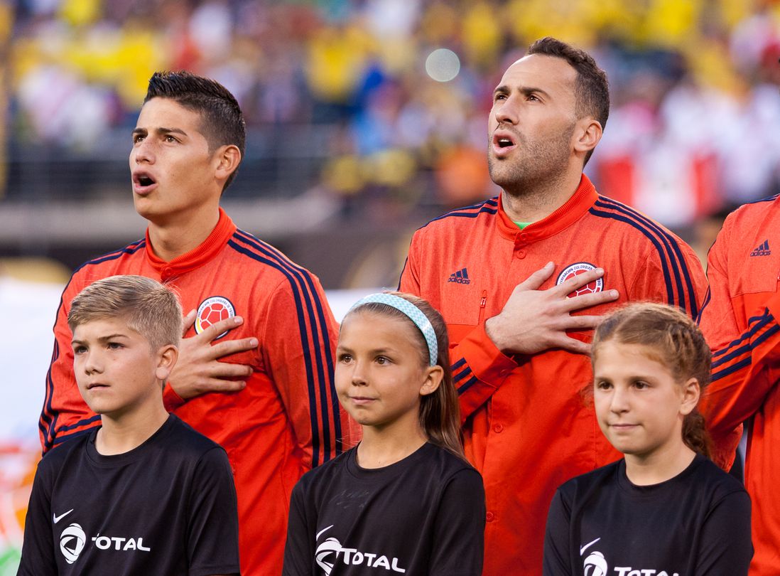 Colombia's James Rodriguez (left) and David Ospina sing their country's national anthem.